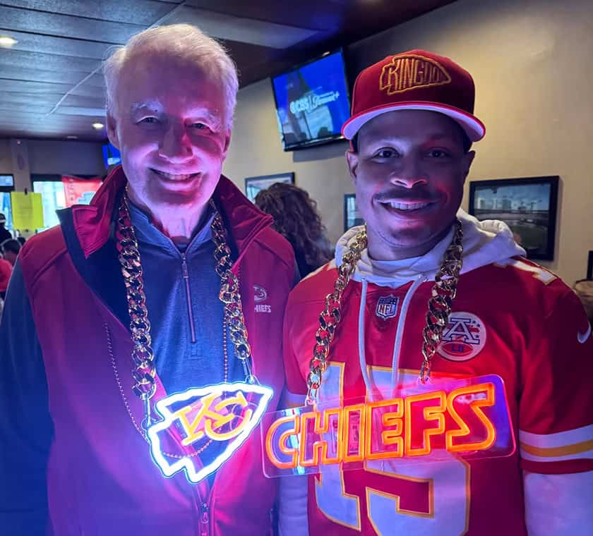 two men wearing neon chains with sports teams on them